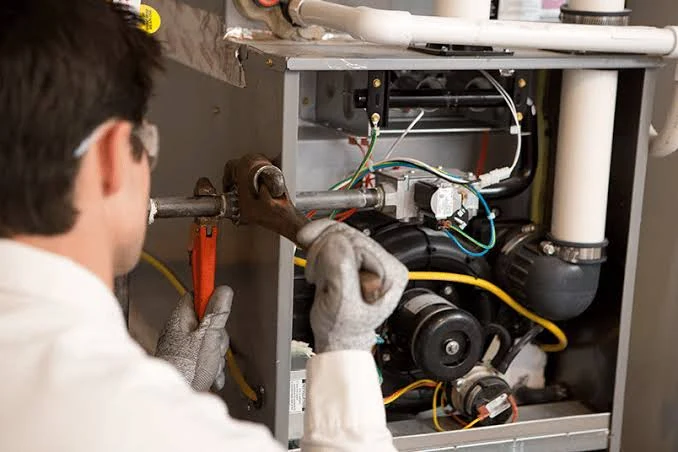 Service technician inspecting components inside a residential furnace