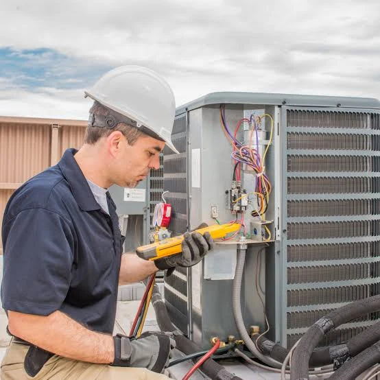 HVAC technician checking an outdoor unit with a diagnostic meter